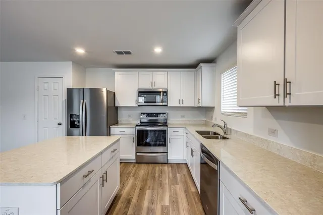 a kitchen with a sink a stove a refrigerator a center island and cabinets