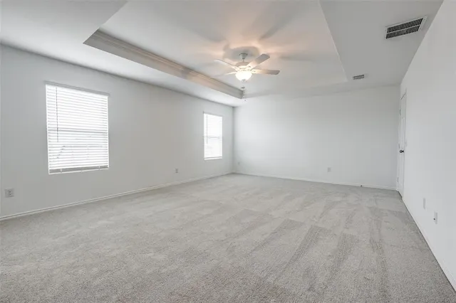 an empty room with windows and chandelier fan