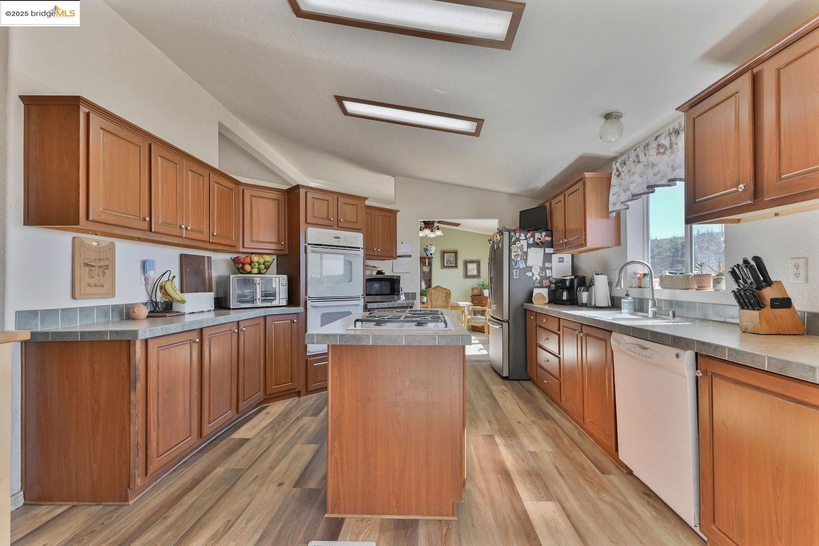 3770 Sheep Ranch Road Murphys, CA 95247 - Photo 17 of 60 a kitchen with stainless steel appliances granite countertop wooden cabinets a refrigerator a sink a stove and a microwave oven with wooden floor