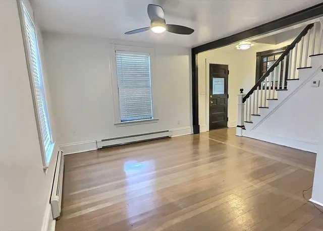 a view of an empty room with wooden floor and a window