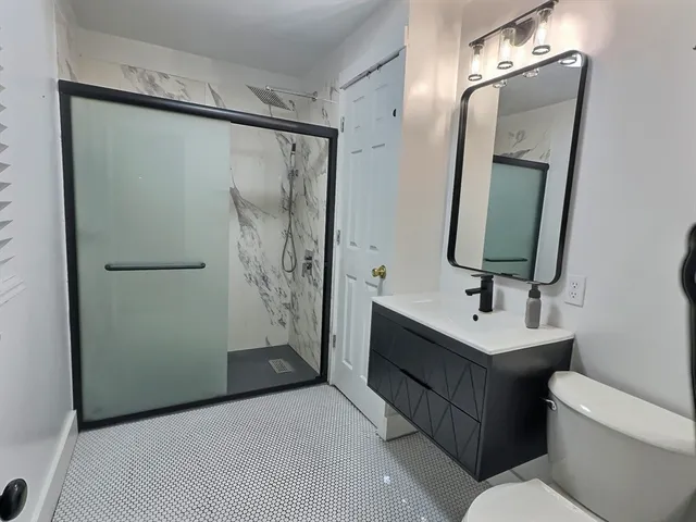 a bathroom with a double vanity sink toilet mirror and shower