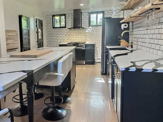 a kitchen with stainless steel appliances granite countertop a sink a stove and chairs