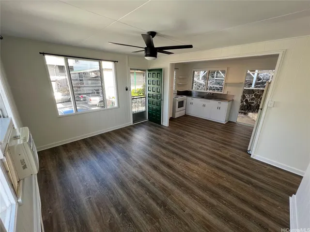 a view of a livingroom with wooden floor a ceiling fan and windows