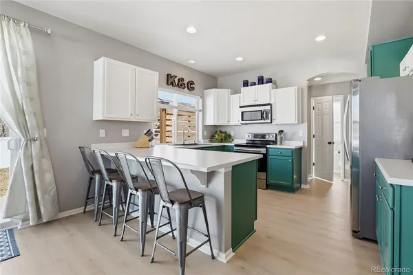 a kitchen with stainless steel appliances granite countertop a refrigerator a stove a sink a dining table and chairs with wooden floor