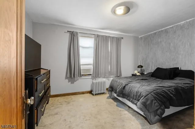 a spacious bedroom with a bed and a flat tv screen on the dresser