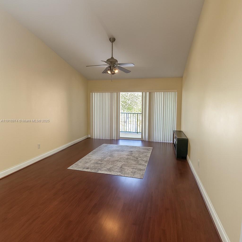 8801 Wiles Road, Unit 307 Coral Springs, FL 33067 - Photo 3 of 10 an empty room with wooden floor fan and windows