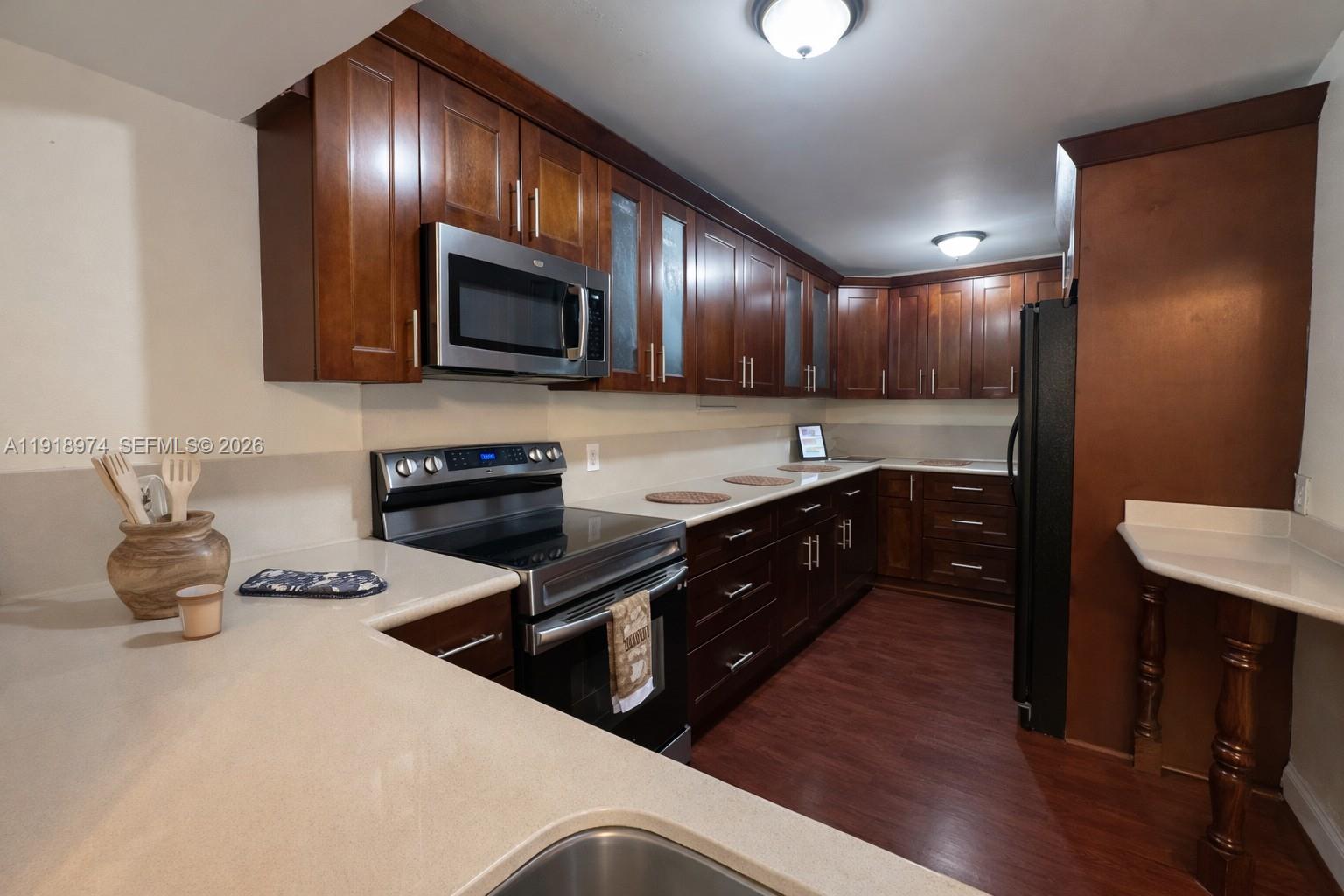 8801 Wiles Road, Unit 307 Coral Springs, FL 33067 - Photo 4 of 16 a kitchen with a sink and a stove top oven with wooden floor