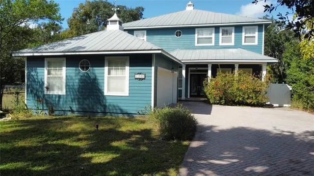 an aerial view of a house with a yard and large trees