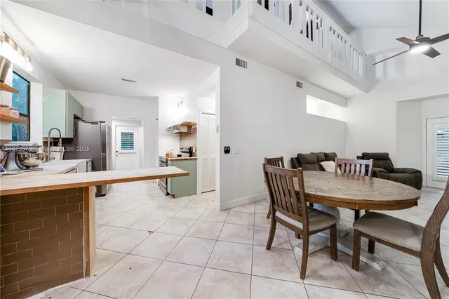a kitchen with stainless steel appliances a dining table chairs and view living room