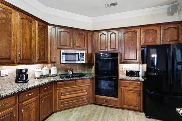 a kitchen with granite countertop wooden cabinets and refrigerator