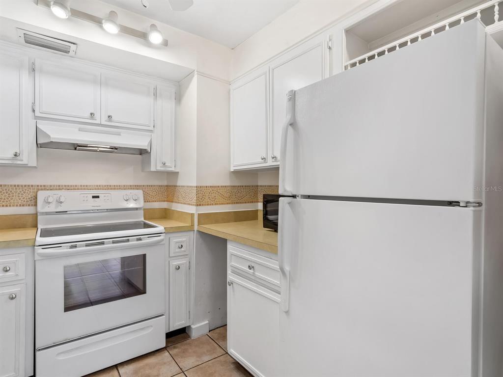 4805 Rilma Avenue, Unit 107 Sarasota, FL 34234 - Photo 14 of 42 a kitchen with stainless steel appliances white cabinets and white appliances