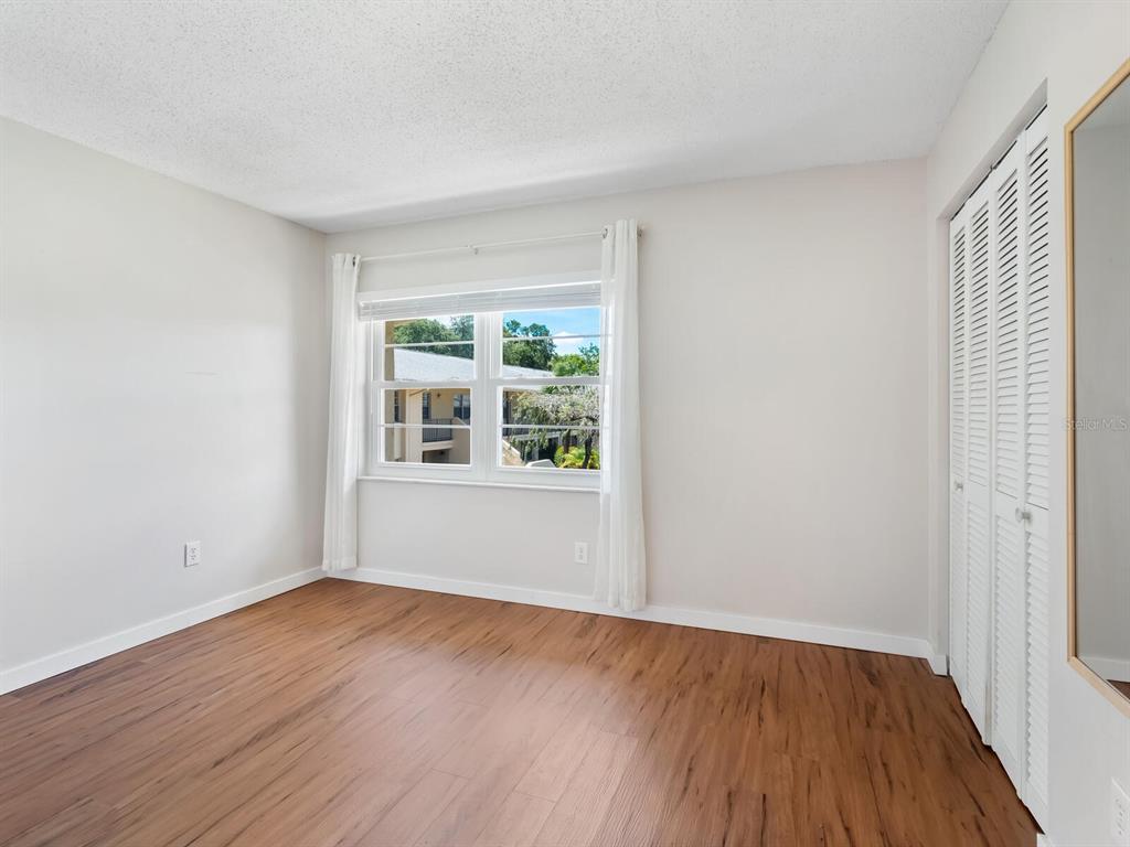 4805 Rilma Avenue, Unit 107 Sarasota, FL 34234 - Photo 22 of 42 a view of an empty room with wooden floor and a window