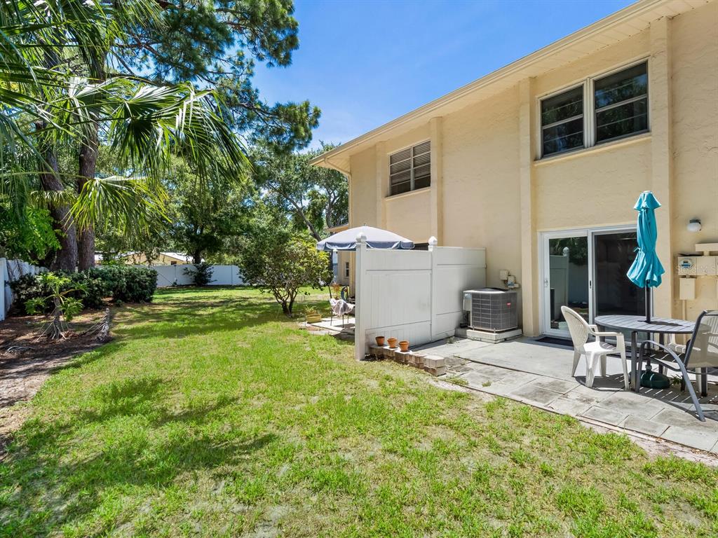 4805 Rilma Avenue, Unit 107 Sarasota, FL 34234 - Photo 27 of 42 a view of a patio with table and chairs with wooden fence and plants