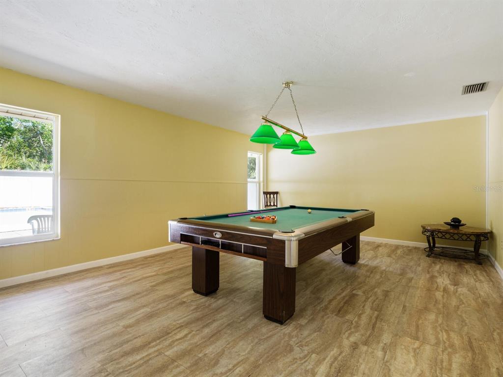 4805 Rilma Avenue, Unit 107 Sarasota, FL 34234 - Photo 37 of 42 a room with wooden floor pool table and windows