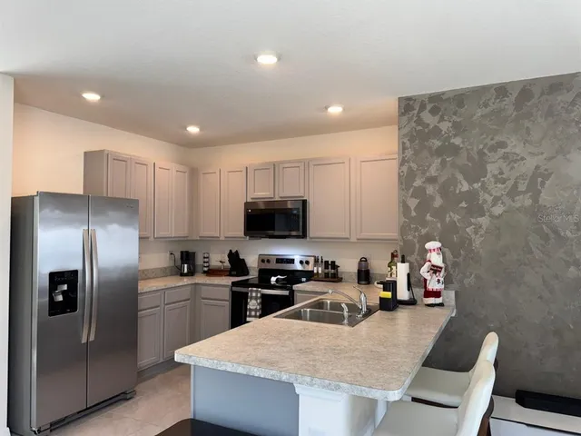 a kitchen with granite countertop a sink a counter top space stainless steel appliances and cabinets