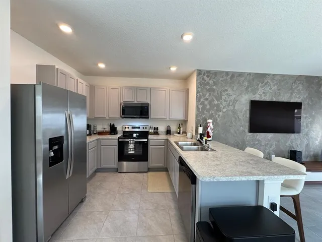 a kitchen with sink a refrigerator and chairs