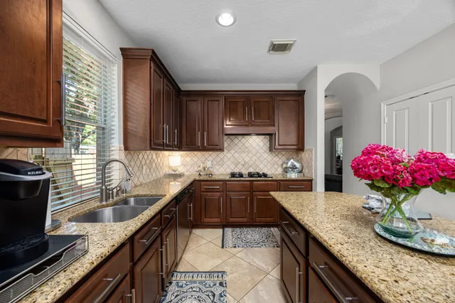 a kitchen with granite countertop a sink stove and cabinets