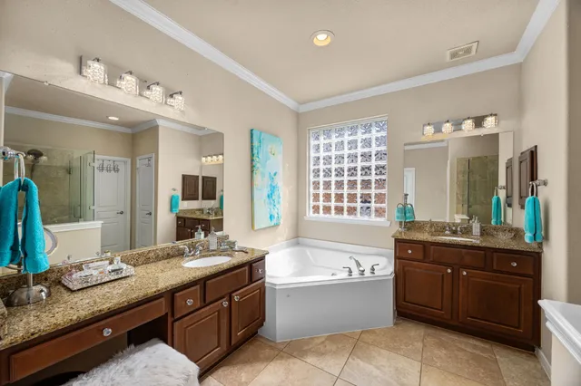 a spacious bathroom with a granite countertop double vanity sink a bathtub mirror and double