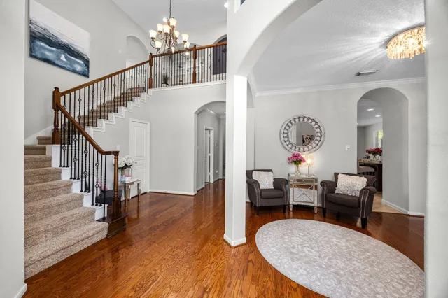 a living room with couches chandelier and a dining table with wooden floor