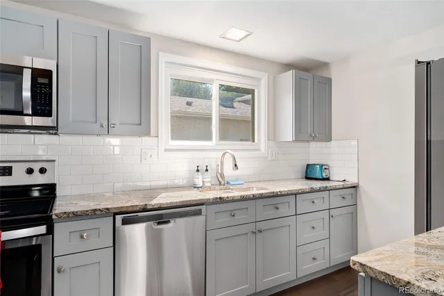 a kitchen with granite countertop cabinets stainless steel appliances a sink and window