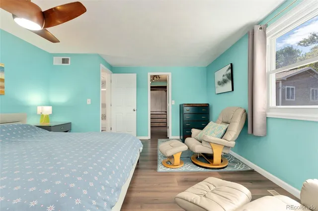 a bedroom with a bed wooden floor and a lamp on dresser