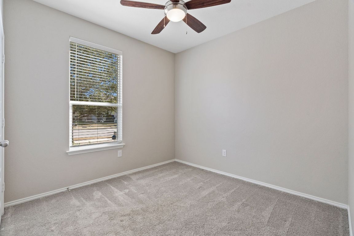 7504 Groundhog Way Austin, TX 78744 - Photo 16 of 22 Secondary bedroom 1 features a ceiling fan and closet.