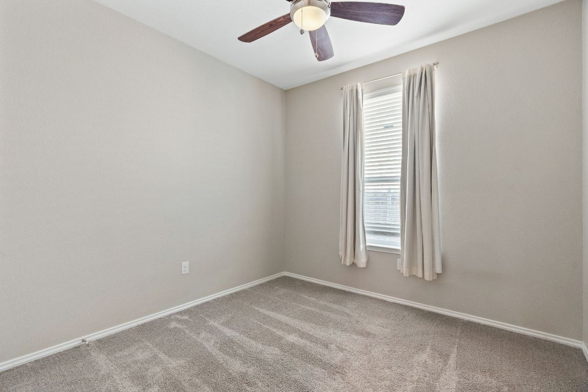 7504 Groundhog Way Austin, TX 78744 - Photo 17 of 22 Secondary bedroom 2 features a ceiling fan and closet.