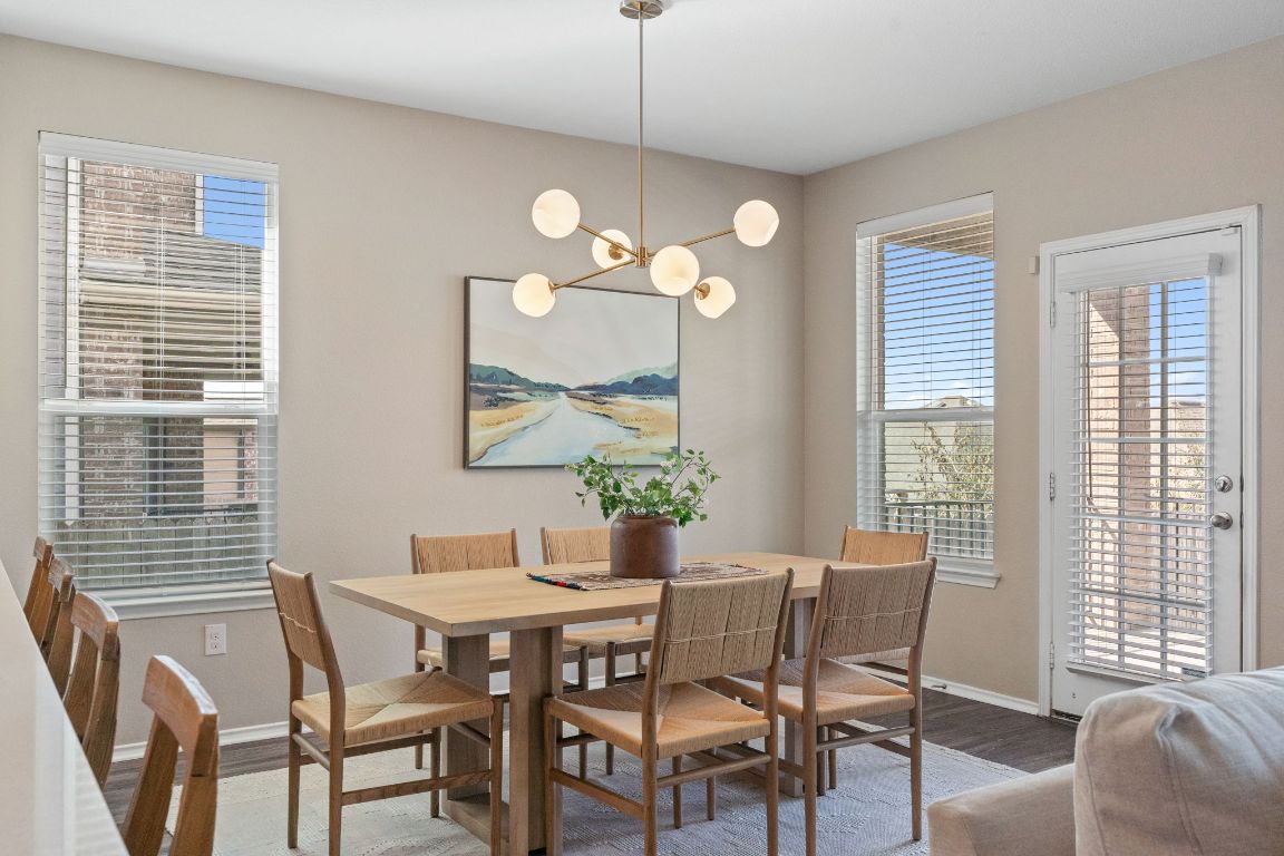 7504 Groundhog Way Austin, TX 78744 - Photo 5 of 22 The dining area has a modern chandelier and natural light streaming from multiple windows.