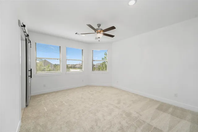 an empty room with chandelier fan and windows