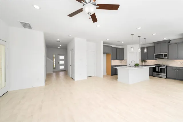 a view of kitchen with stainless steel appliances refrigerator stove top oven and cabinets