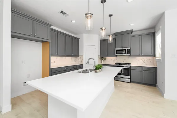 a kitchen with kitchen island a stove a sink a refrigerator and cabinets