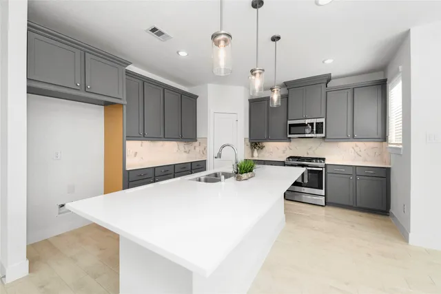 a kitchen with kitchen island a stove a sink a refrigerator and cabinets