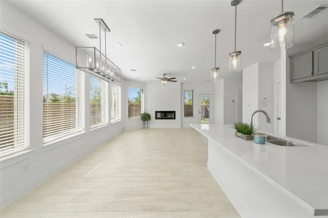 a large white kitchen with kitchen island a large window a sink and stainless steel appliances