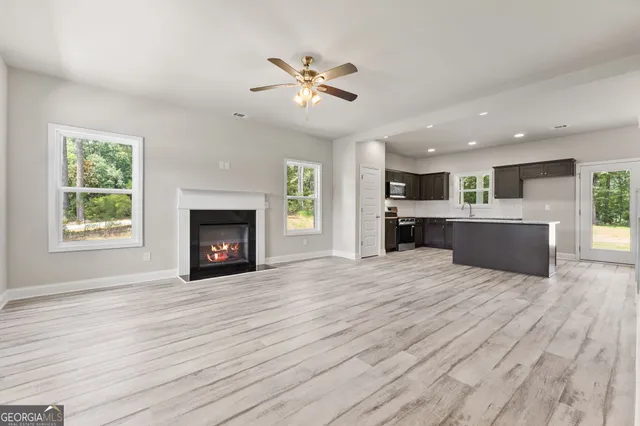 a large kitchen with stainless steel appliances kitchen island granite countertop a stove a sink dishwasher and a microwave with wooden floor