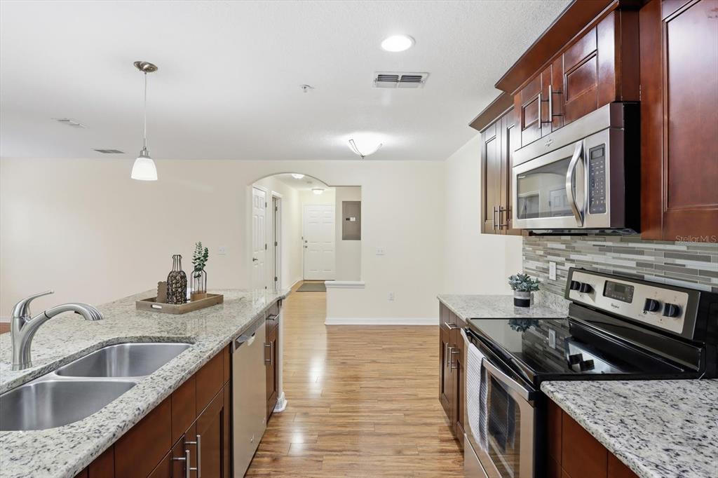 5041 Royal Palms Way, Unit 202 New Port Richey, FL 34652 - Photo 11 of 41 a kitchen with stainless steel appliances granite countertop a sink stove and cabinets