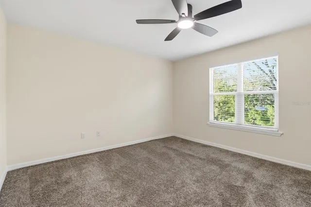 an empty room with windows and ceiling fan