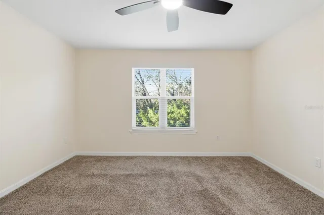 an empty room with a ceiling fan and a window