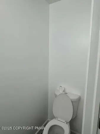 a white toilet sitting next to a white wall
