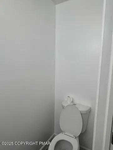 a white toilet sitting next to a white wall