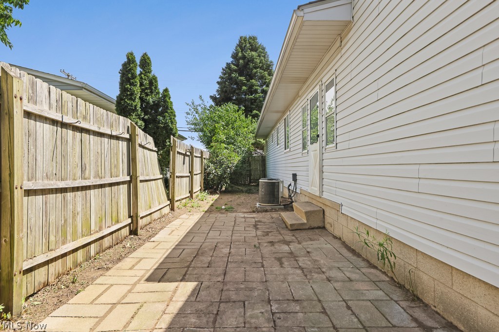 611 Herbert Road Akron, OH 44312 - Photo 5 of 30 Paved patio area featuring a wooden privacy fence and a white siding exterior