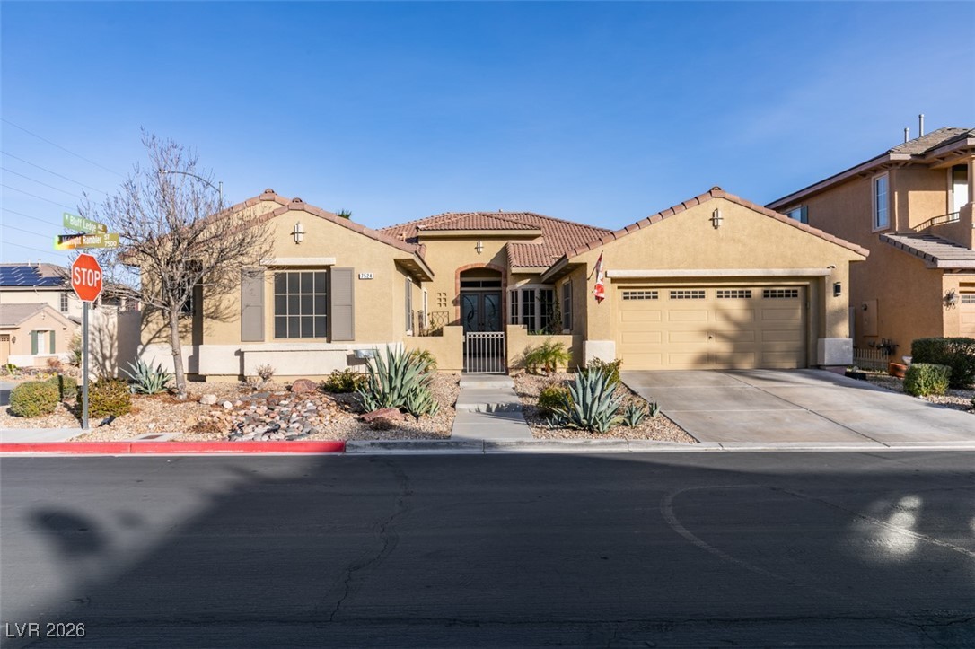 Mediterranean / spanish house featuring stucco siding, a gate, a tile roof, an attached garage, and concrete driveway