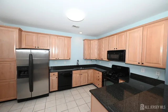 a kitchen with stainless steel appliances granite countertop a refrigerator a stove a sink and a microwave