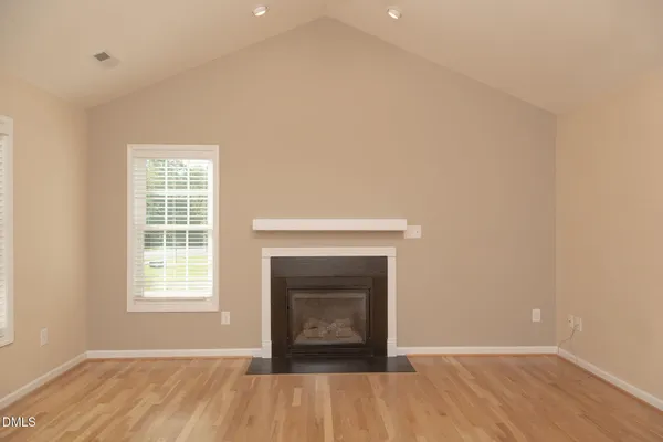an empty room with wooden floor a fireplace and windows