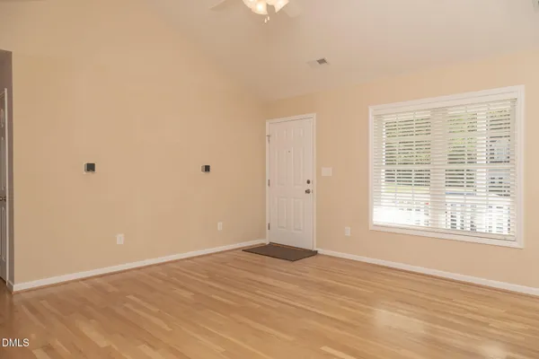 a view of an empty room with wooden floor and a window