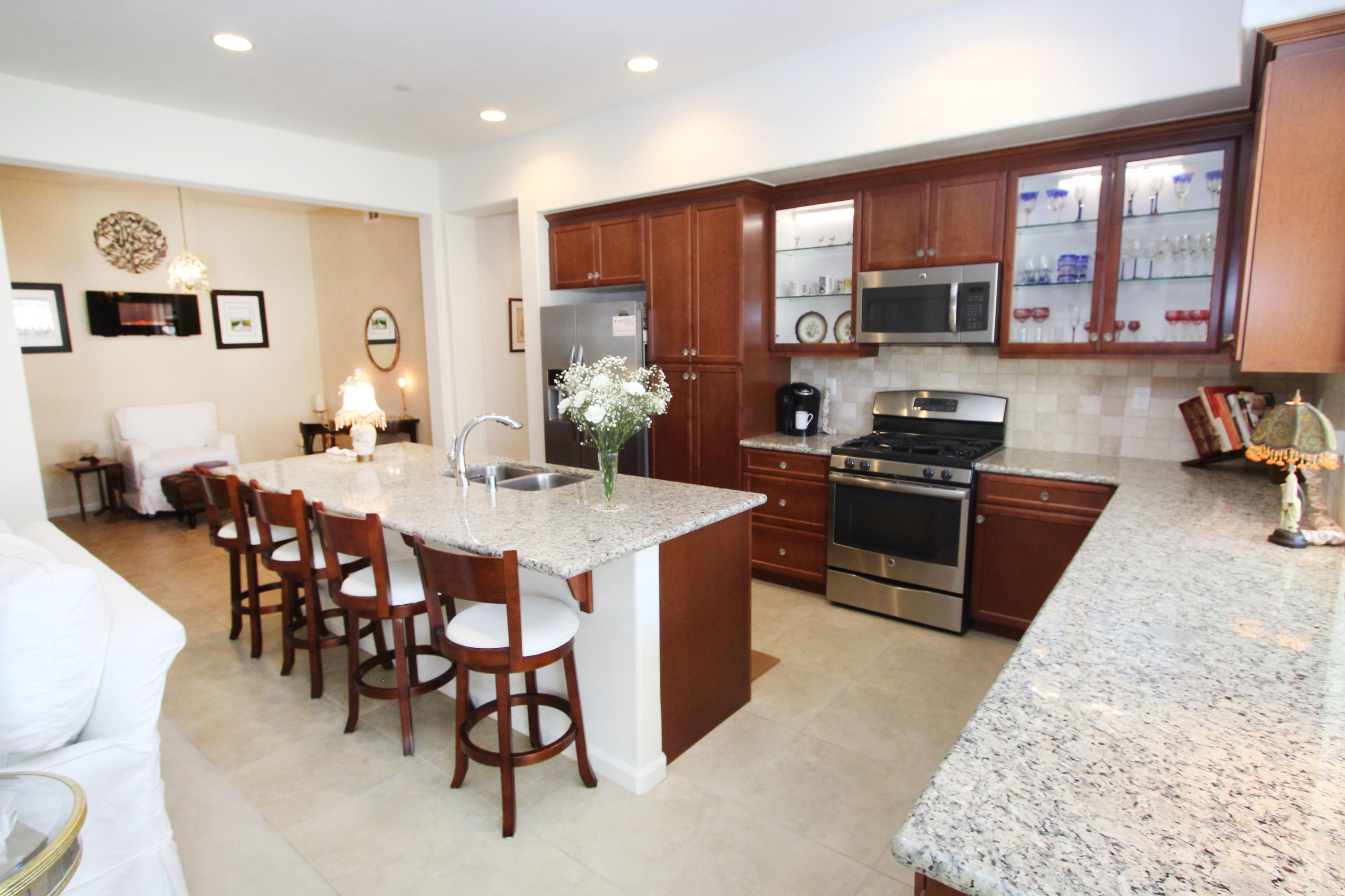 a kitchen with stainless steel appliances granite countertop a stove a sink a refrigerator a dining table and chairs