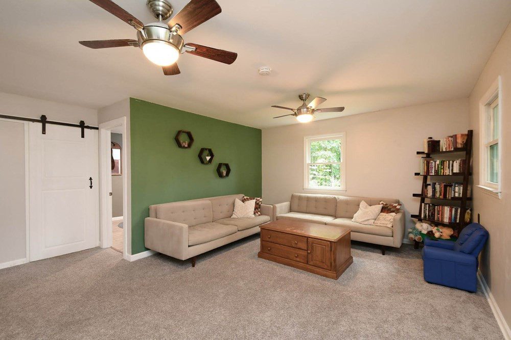 7701 Cresthill Court Raleigh, NC 27615 - Photo 16 of 29 Family Room with ceiling fans, natural light from windows, and barn door is access to Laundry Room. Family Room