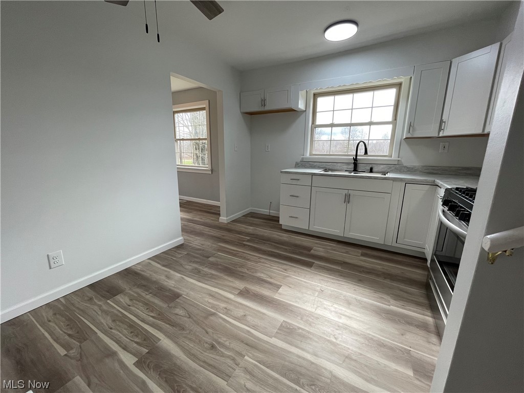 6135 California Road Williamsfield, OH 44093 - Photo 13 of 37 Kitchen with sink, gray cabinetry, stainless steel gas range oven, ceiling fan, and light hardwood / wood-style flooring