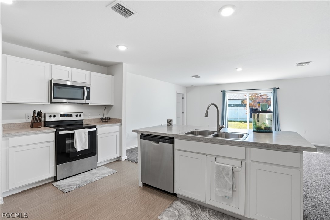 3319 40th Street West Lehigh Acres, FL 33971 - Photo 2 of 45 a kitchen with white cabinets and stainless steel appliances