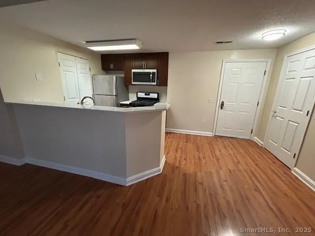 a living room with stainless steel appliances wooden floors and view living room