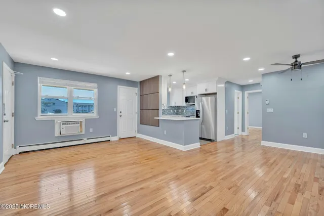 a view of a kitchen with kitchen island wooden floor appliances and cabinets